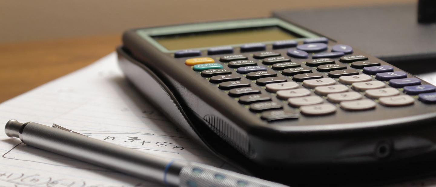 Calculadora científica sobre caderno de anotações com contas matemáticas